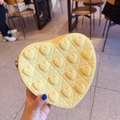 Detail of beige heart-shaped crossbody bag with quilted diamond pattern and stud accents - Yellow