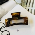 Close-up of a translucent coffee amber rectangular hair claw clip on a white book page - Glossy Light Tortoise