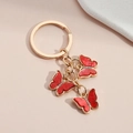 Colorful acrylic butterfly keychain with sparkling red charms and golden ring on beige base - Red
