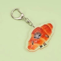 Funny crying cat croissant acrylic keychain with a silver metal clasp on green background - Bread Style