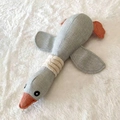 Gray goose plush squeaky dog toy with linen texture and orange feet on white fur rug - Gray