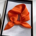 Vibrant orange silk square scarf folded into a bow inside a white gift box - Orange