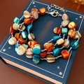 Dettaglio di un bracciale multistrato bohemian con perline di conchiglia colorate e chiusura - Multicolore