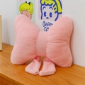 Pink faux rabbit fur bow pillow with elegant ribbons on a minimalist wooden surface - Pink
