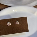 Close-up of pink square zircon earrings with gold bow detail on a dark display card - Lock Bowknot / Earring Posts