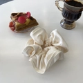 Close-up of cream satin scrunchie with soft ruffled edges in a cozy lifestyle setting - Classic White