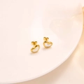 Close-up of golden heart earrings with white shell inlay on a ceramic display tray - ED3041J Mother of Pearl Heart Stud Earrings Gold