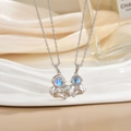 Close-up of astronaut couple necklace with blue zircon inlay on white silk backdrop - Silver Blue Stone Astronaut Set XL0487G