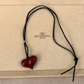 Detail van rode hars hartvormige hanger aan zwart koord in een beige display - Rood Hart (HN7575)