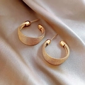 Fashionable gold C-shaped hoop earrings with woven metal texture on elegant silk background - Gold Stud Earring Style
