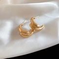 Macro detail of gold-plated double-layer C-shaped hoop earrings on white silk fabric - Gold