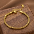 Gold mesh chain bracelet with cylindrical accents and adjustable lobster clasp on wood - Gold