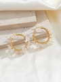 Detailed macro view of bohemian gold hoop earrings featuring natural clear crystal stones - White