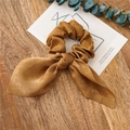 Elegant champagne gold satin scrunchie with rabbit ear bow on a wooden background - Coffee