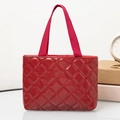 Detail of red quilted tote bag featuring glossy patent texture and nylon webbing handles - Horizontal / Red