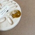 Detailed view of amber translucent resin ring on a textured tray with a gift card - Light Coffee/Light Amber