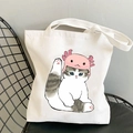 White canvas tote bag with a cute cat wearing a pink axolotl hat on a black chair - Cat in Axolotl Hat