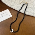 Detail of black faceted crystal bead necklace with a white crescent moon pendant on fabric - Black Crescent Moon Pendant Necklace