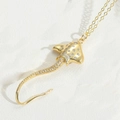 Pendentif raie dorée élégant avec pavé de zircons blancs sur fond blanc texturé - Raie