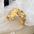 Macro-opname van een gouden brede armband met onregelmatige lava-textuur - Goud Geplooide Stijl
