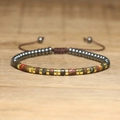 Detailed macro view of woven bracelet with emperor stones and adjustable slider knot - No.70 Hematite Picasso Gold