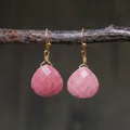 Macro detail of pink teardrop emperor stone earrings with gold wire wrap on a wooden branch - Sakura Pink Faceted Teardrop Style (ER1060-1)