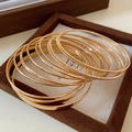 Set of multi-layered gold plated bangles with smooth and beaded texture in a wooden tray - Gold Set Style