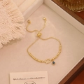 Dettaglio del bracciale regolabile con perline dorate, occhio del male e zirconi - Stile Doppio Pendente (Q)