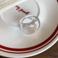 Dettaglio di un anello ovale in resina trasparente su un piatto con scritta decorativa - Trasparente