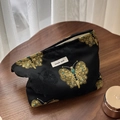 Detailed close-up of butterfly embroidery and 'simple wish' label on a black fabric pouch - Butterfly Embroidery / Black Gold Butterfly