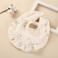 Gros plan d'un bavoir en coton pour bébé avec imprimé floral vert et bords à volants - Fleur