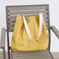 Minimalist bright yellow canvas tote bag with cream wide straps on a grey chair - Yellow