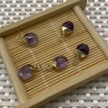 Faceted purple crystal oval pendants with gold-plated edges on a woven tray - Amethyst