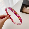 Pink and purple tortoiseshell acetate headband held by hand on white background - Purple