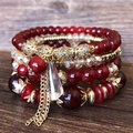 Nahaufnahme des böhmischen Perlenarmband-Sets mit roten Perlen und goldenem Quastenanhänger - Dunkelrot