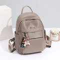 Mochila de tela Oxford beige para mujer con un lindo colgante de osito sobre fondo blanco - Grande / Caqui