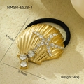Macro shot of gold shell and rhinestone starfish hair tie on a beige stone background - Gold Shell Starfish Rhinestone Hair Tie