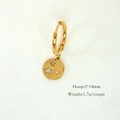 Macro shot of a 14K gold hoop earring with hollow and crystal star pendant on fabric - Hollow Star
