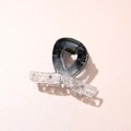 Close-up of a gradient acetate hair claw clip with transparent oval textured details - Cross Black