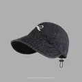 Detailed view of white bow embroidery on black washed denim baseball cap with adjustable strap - Drawstring Wide Brim Sun Hat Style / Black