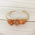 Handmade gold wire-wrapped open cuff bracelet with three raw orange crystal stones - Red Agate