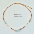 Detail of beaded necklace with pearls, pink stones, and gold heart pendant on white background - Pink Blue Colorful Stone (1182)
