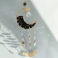 Golden moon suncatcher with black stones and crystals casting rainbow light on wall - M4-Obsidian