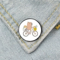 Cute capybara riding a bicycle metal badge pinned on light blue denim jacket fabric - Cycling Capybara