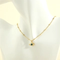 Detailopname van de gouden Evil Eye hanger ketting met blauwe steen op een witte buste - Boze oog