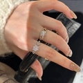 Detailed view of silver sparkling clover and snowflake rings worn on hand by a luxury bag - Adjustable / Silver Clover Ring