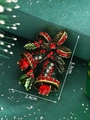 Detailed macro shot of a red and gold Christmas bell brooch with green enamel leaves - Christmas Bell (Red Rhinestone)