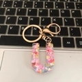 Letter U resin keychain with colorful heart sequins and golden metal clip on keyboard - Letter U