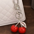 Red cherry resin pendant keychain with silver hardware on a white quilted leather bag - Silver Cherry Pendant