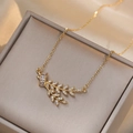 Elegante collana con pendente a foglia dorata e zirconi su una scatola per gioielli grigia - Collana con Pendente Foglia / Stile Foglia d'Oro (X0177)